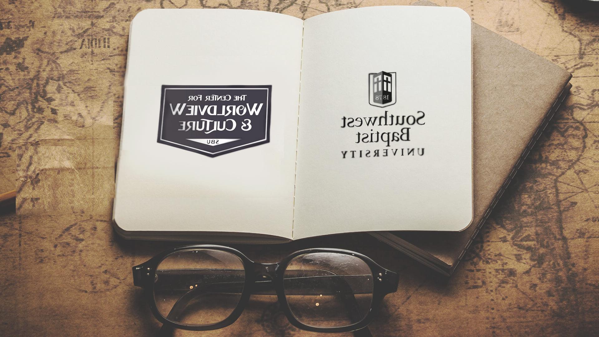 open notebook next to folded glasses with S-B-U and Worldview Center logos